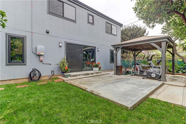 rear view of property with a gazebo, a lawn, and a patio