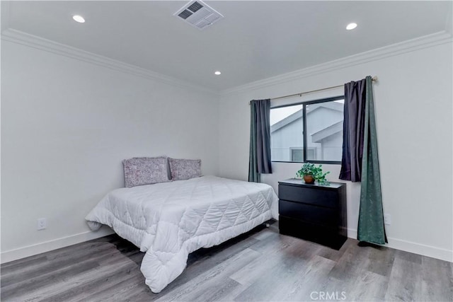 bedroom featuring baseboards, ornamental molding, wood finished floors, and visible vents