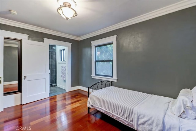 bedroom featuring wood-type flooring, ornamental molding, baseboards, and ensuite bath