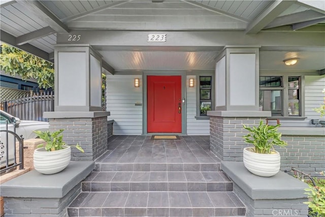 entrance to property with fence and covered porch