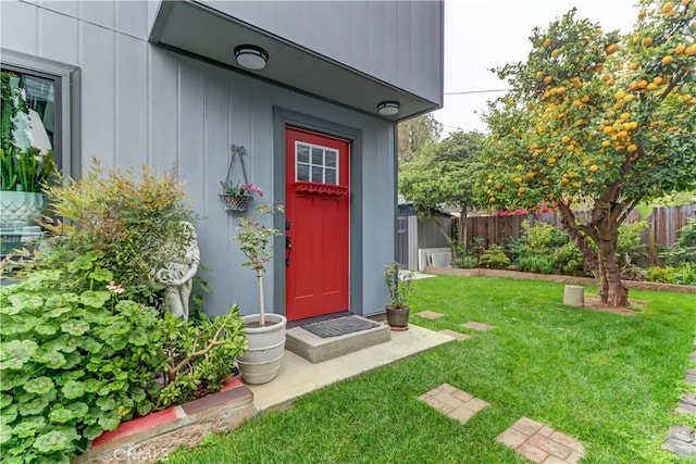 doorway to property featuring a lawn and fence