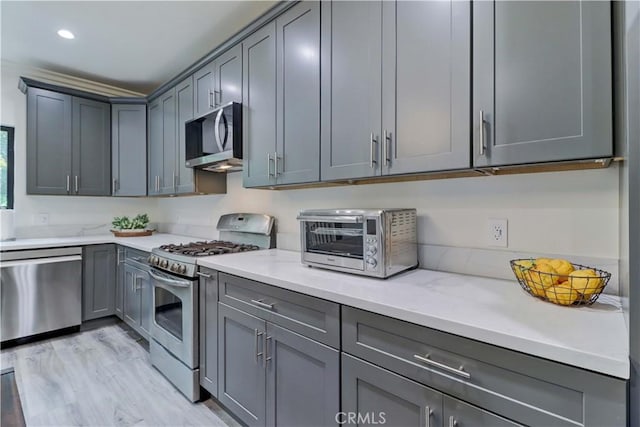 kitchen with gray cabinets, a toaster, light stone countertops, and stainless steel appliances