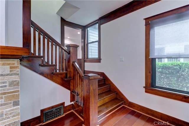 stairway with baseboards, visible vents, and wood finished floors