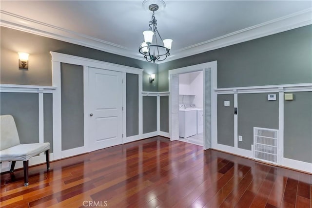 unfurnished dining area featuring visible vents, ornamental molding, wood finished floors, washer and clothes dryer, and a notable chandelier