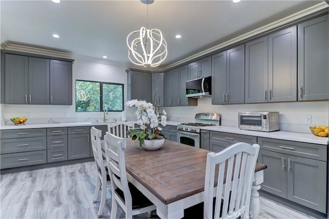 kitchen featuring crown molding, an inviting chandelier, stainless steel appliances, a toaster, and gray cabinetry