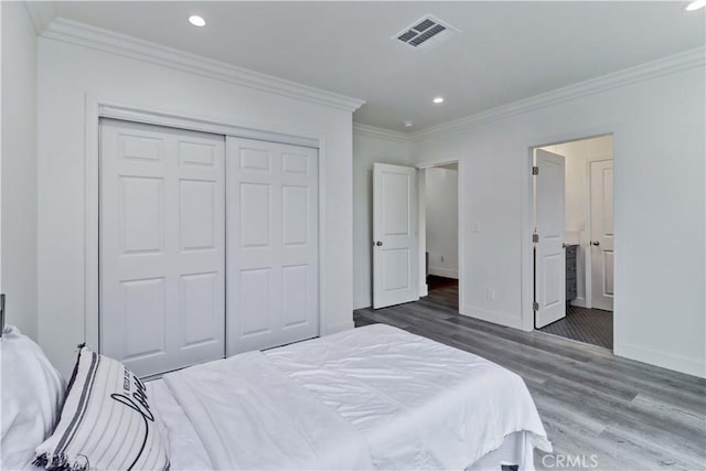 bedroom with visible vents, ornamental molding, a closet, wood finished floors, and baseboards