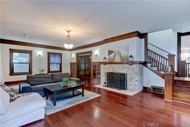 living room with stairs, visible vents, wood finished floors, and a fireplace