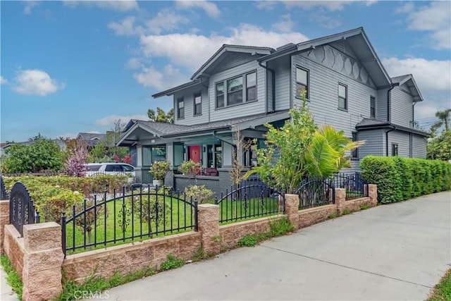 craftsman-style house with a porch, board and batten siding, a fenced front yard, and a front yard