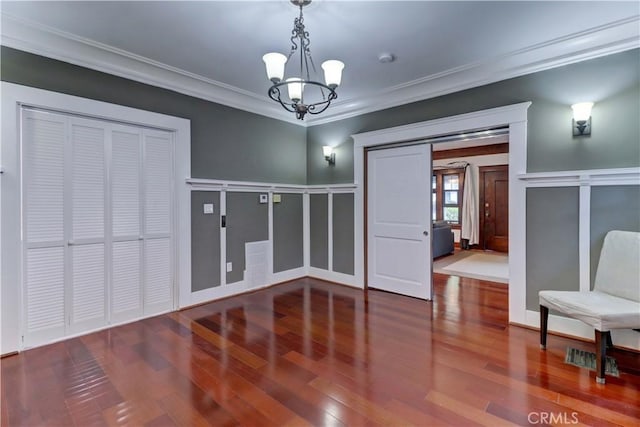 unfurnished dining area featuring an inviting chandelier, ornamental molding, and wood finished floors
