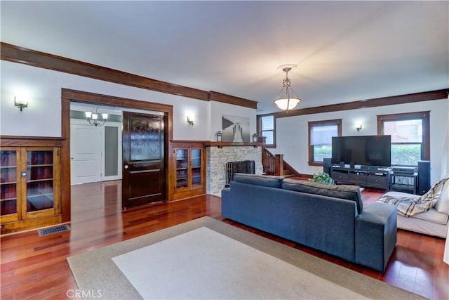 living room with a stone fireplace, wood finished floors, and visible vents