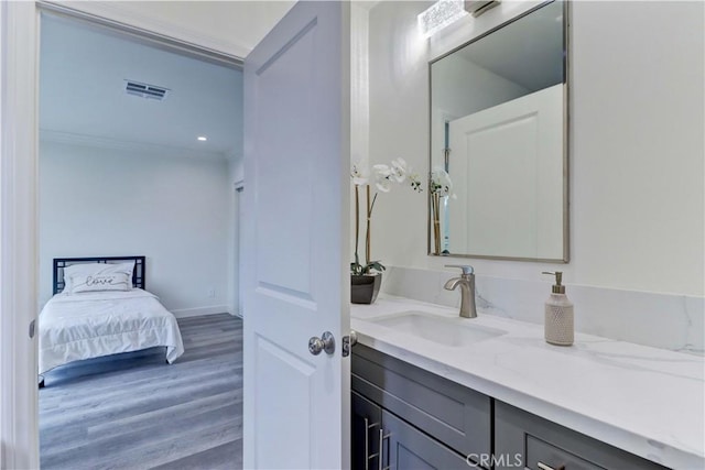 bathroom with crown molding, vanity, wood finished floors, ensuite bathroom, and visible vents