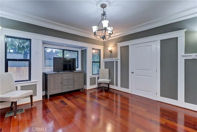 living area with ornamental molding, a notable chandelier, visible vents, and dark wood-type flooring