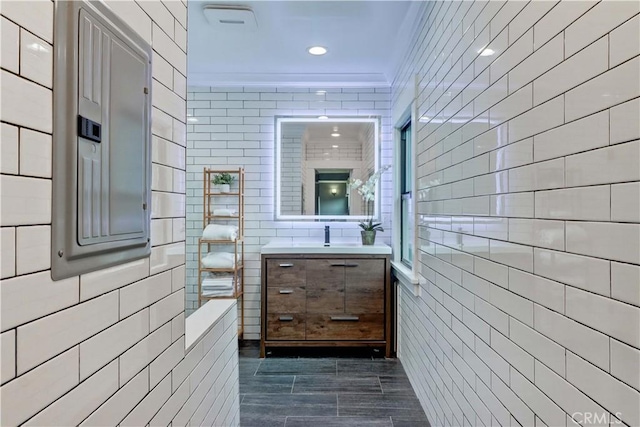 bathroom with walk in shower, tile walls, vanity, and recessed lighting
