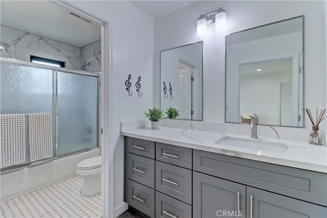 full bathroom with toilet, visible vents, bath / shower combo with glass door, and vanity
