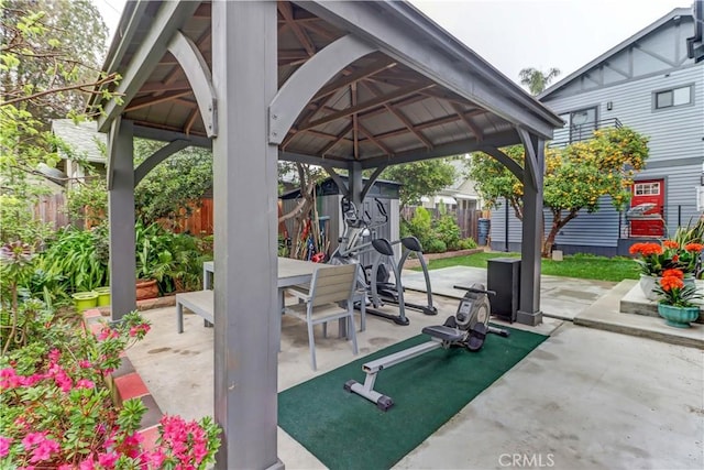 view of patio featuring an outbuilding, a gazebo, a fenced backyard, a shed, and outdoor dining space