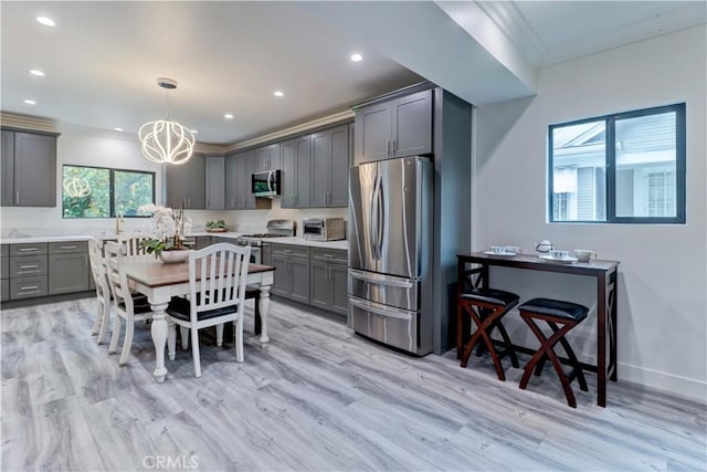 kitchen with appliances with stainless steel finishes, ornamental molding, gray cabinets, and light wood-style floors
