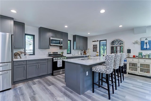 223 N St Andrews Pl, Los Angeles, CA 90004 - kitchen with stainless steel appliances, a kitchen bar, recessed lighting, light wood-style floors, and a kitchen island with sink