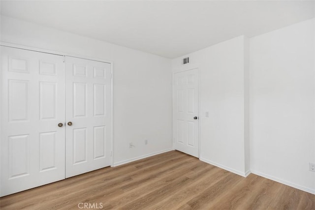unfurnished bedroom featuring a closet, baseboards, visible vents, and light wood-type flooring