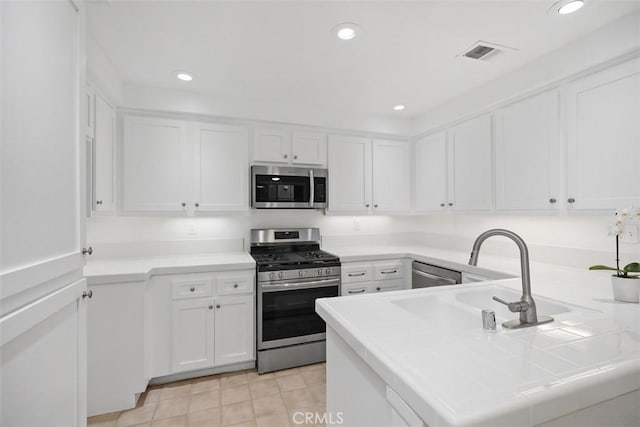 kitchen featuring appliances with stainless steel finishes, a peninsula, and white cabinetry