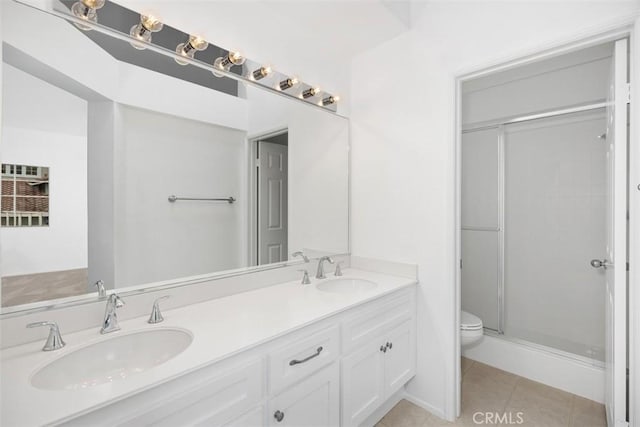 full bathroom featuring toilet, a sink, tile patterned flooring, and a stall shower