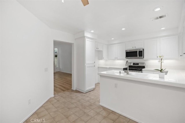 kitchen with visible vents, a peninsula, recessed lighting, white cabinets, and appliances with stainless steel finishes