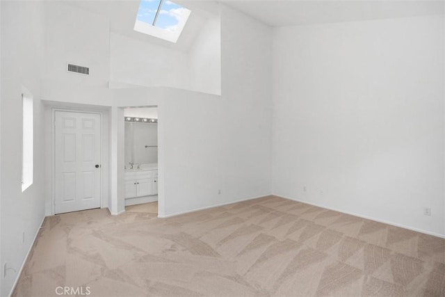 unfurnished bedroom featuring light colored carpet, a skylight, visible vents, and high vaulted ceiling