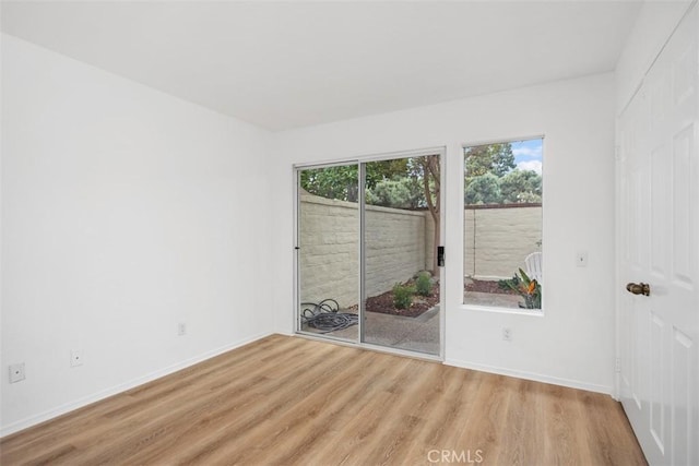 empty room featuring baseboards and light wood finished floors