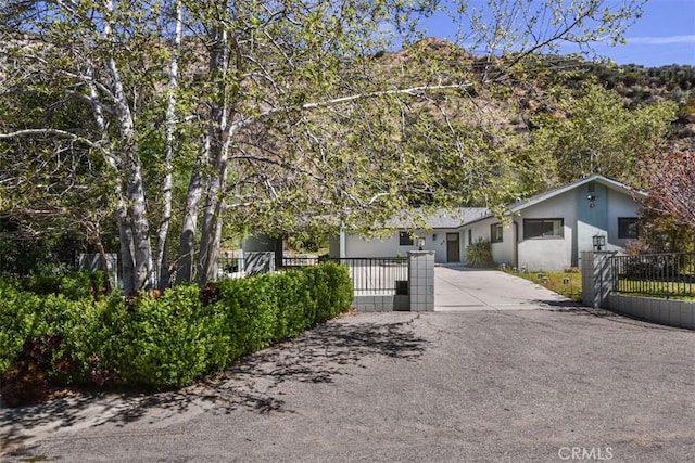 2447 Stonyvale Rd, Tujunga, CA 91042 - view of front of house with concrete driveway, a fenced front yard, stucco siding, and a gate