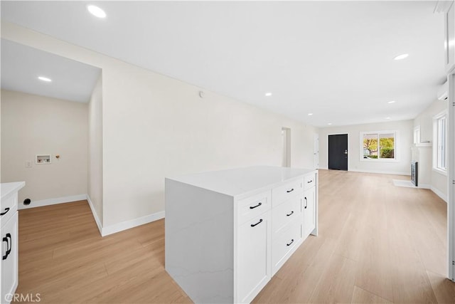 kitchen featuring baseboards, open floor plan, light countertops, white cabinets, and light wood finished floors