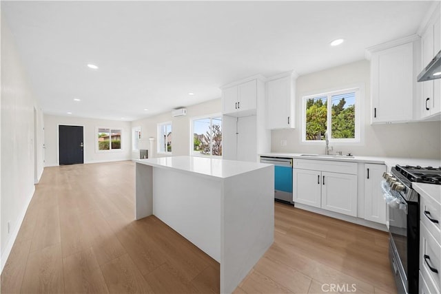 kitchen featuring dishwashing machine, light wood-type flooring, a center island, a sink, and black gas range oven