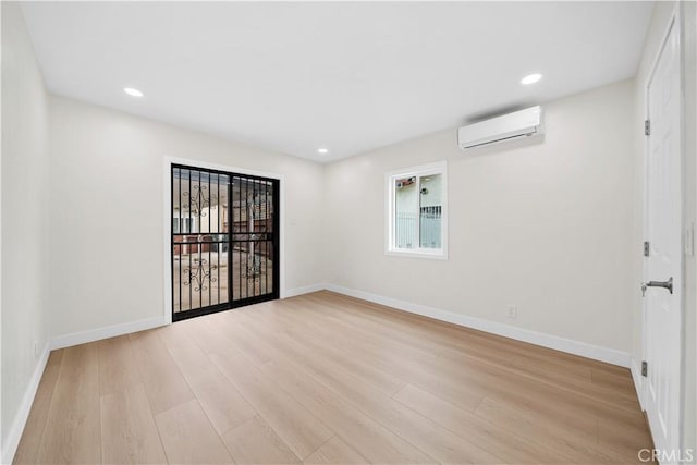 unfurnished room with recessed lighting, an AC wall unit, baseboards, and wood finished floors