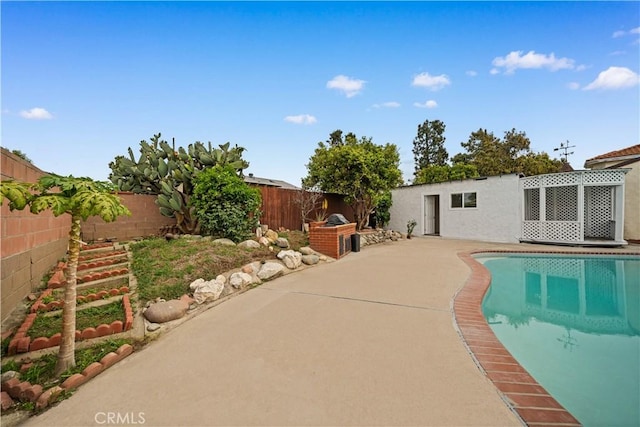 view of swimming pool with an outdoor kitchen, a fenced backyard, a fenced in pool, and a patio area