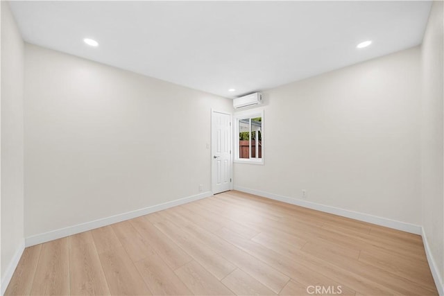 spare room with a wall mounted AC, light wood finished floors, baseboards, and recessed lighting