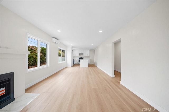 unfurnished living room featuring baseboards, recessed lighting, light wood-style floors, a wall unit AC, and a tile fireplace