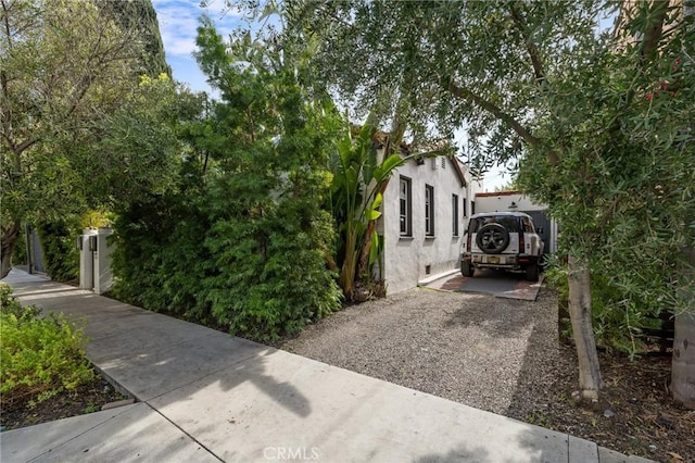 view of side of property with stucco siding and gravel driveway
