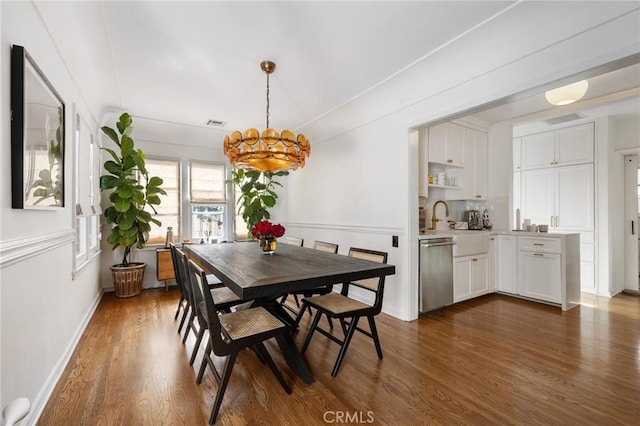 dining room with dark wood-style flooring, visible vents, and a notable chandelier