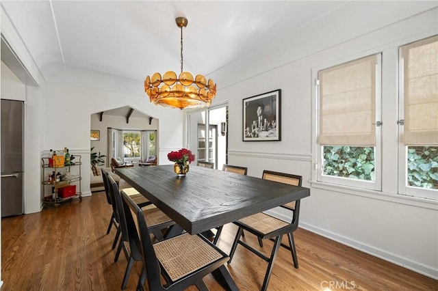 dining area featuring baseboards, wood finished floors, and an inviting chandelier