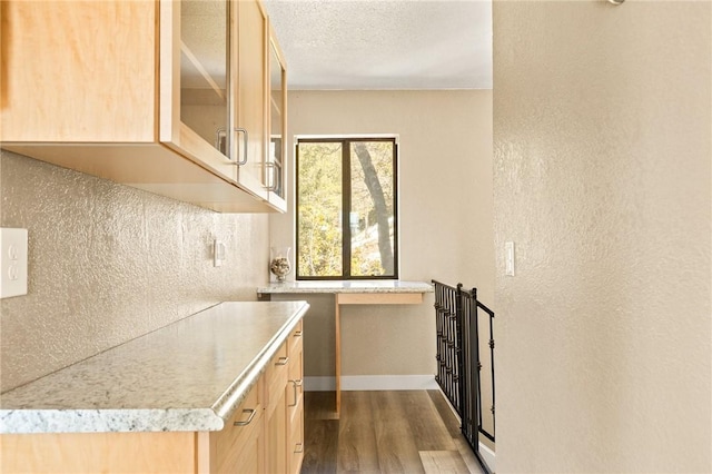 27596 N Bay Rd, Lake Arrowhead, CA 92352 - kitchen with light brown cabinetry, dark wood finished floors, light countertops, glass insert cabinets, and a textured wall