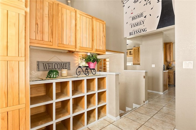 27596 N Bay Rd, Lake Arrowhead, CA 92352 - kitchen featuring light tile patterned floors, light brown cabinets, baseboards, light countertops, and a towering ceiling