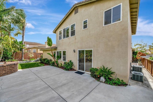 back of house with fence, stucco siding, and a patio