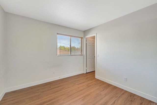 unfurnished room featuring baseboards and light wood-type flooring