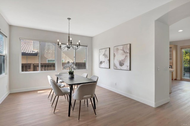 dining room with baseboards, a healthy amount of sunlight, wood finished floors, and a chandelier