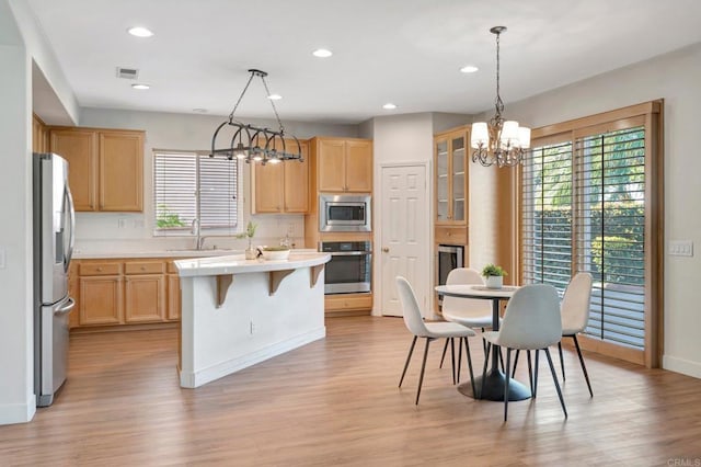 kitchen featuring light countertops, stainless steel appliances, an inviting chandelier, and light brown cabinetry
