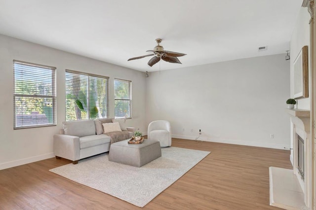 living area with baseboards, light wood-style flooring, ceiling fan, and visible vents