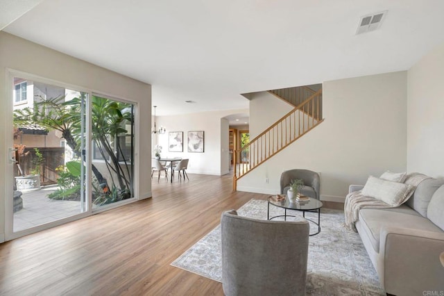 living room featuring visible vents, baseboards, stairs, wood finished floors, and arched walkways