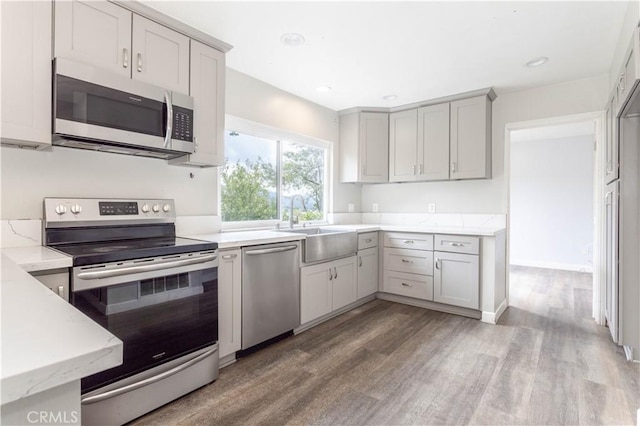 28414 Winterdale Dr, Canyon Country, CA 91387 - kitchen with light stone counters, a sink, light wood finished floors, appliances with stainless steel finishes, and gray cabinetry