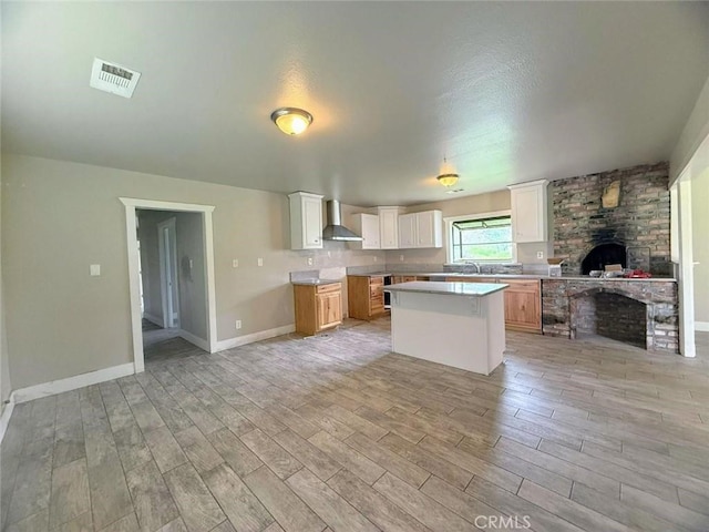 47409 Thunderhill Ln, Squaw Valley, CA 93675 - kitchen with wall chimney exhaust hood, light wood-style flooring, open floor plan, a fireplace, and a center island