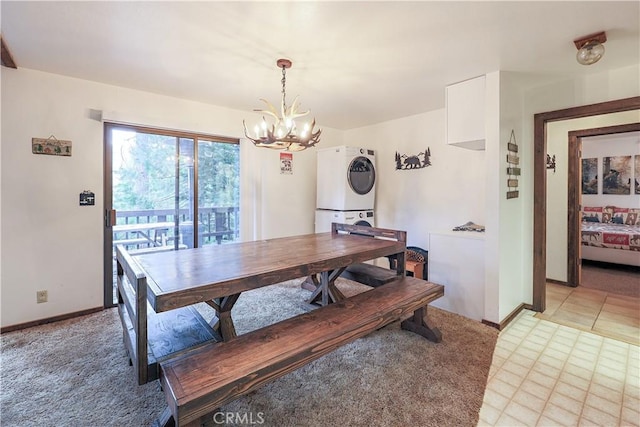 dining room with stacked washer / dryer, a notable chandelier, and baseboards