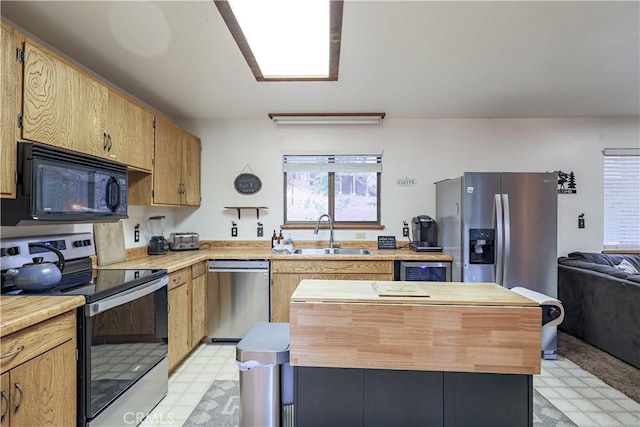 kitchen featuring a sink, a kitchen island, butcher block countertops, light floors, and appliances with stainless steel finishes