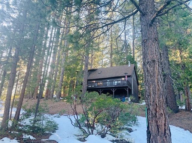 exterior space with a view of trees and a wooden deck
